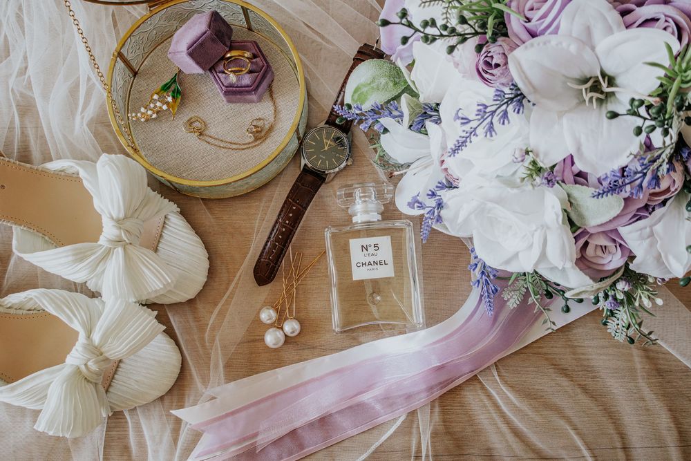 Delicate pink and white floral wedding decorations with ribbons and pearls arranged on a light wooden surface.