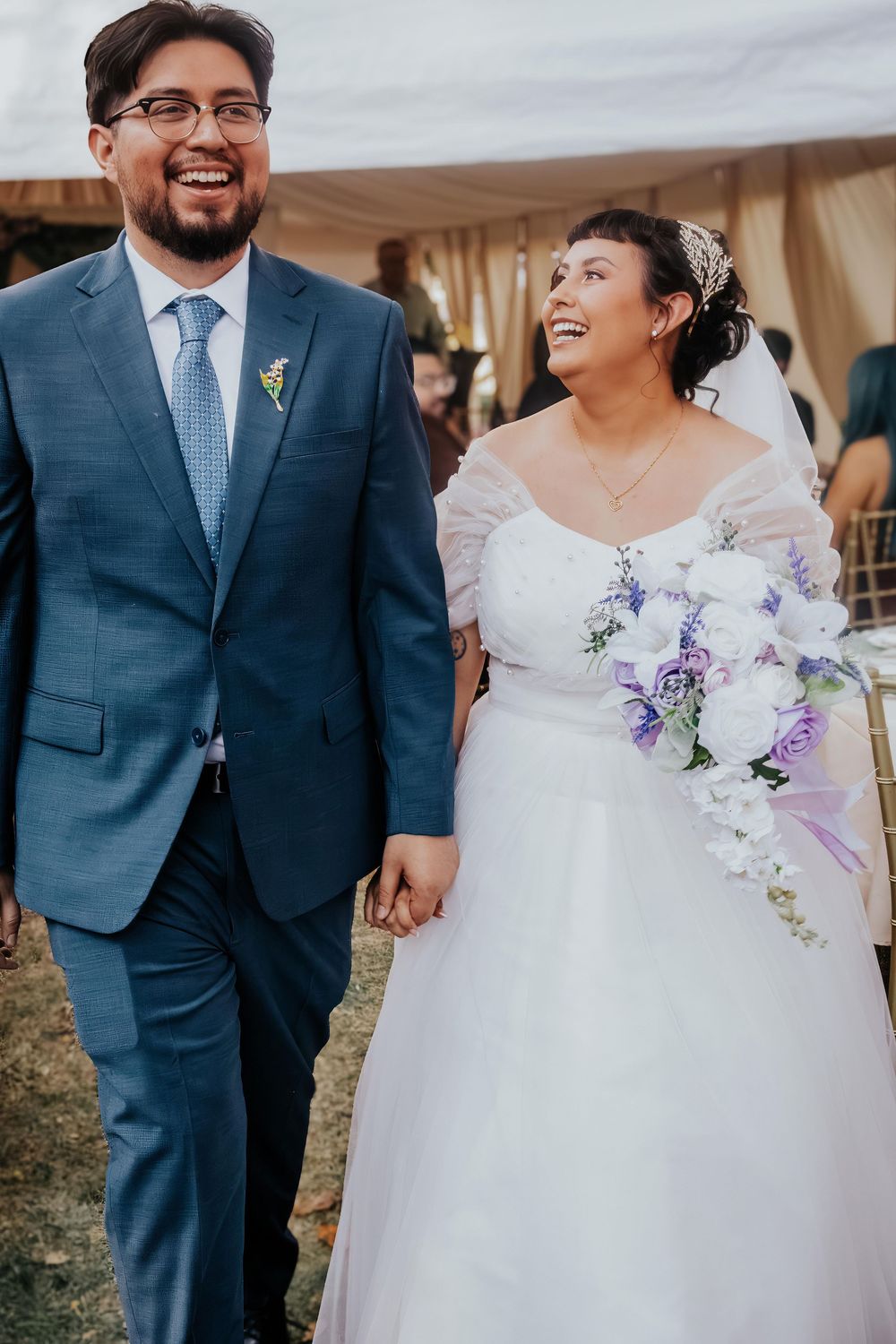 A couple shares joyful moments at their wedding, with the bride in white and groom in navy blue suit.