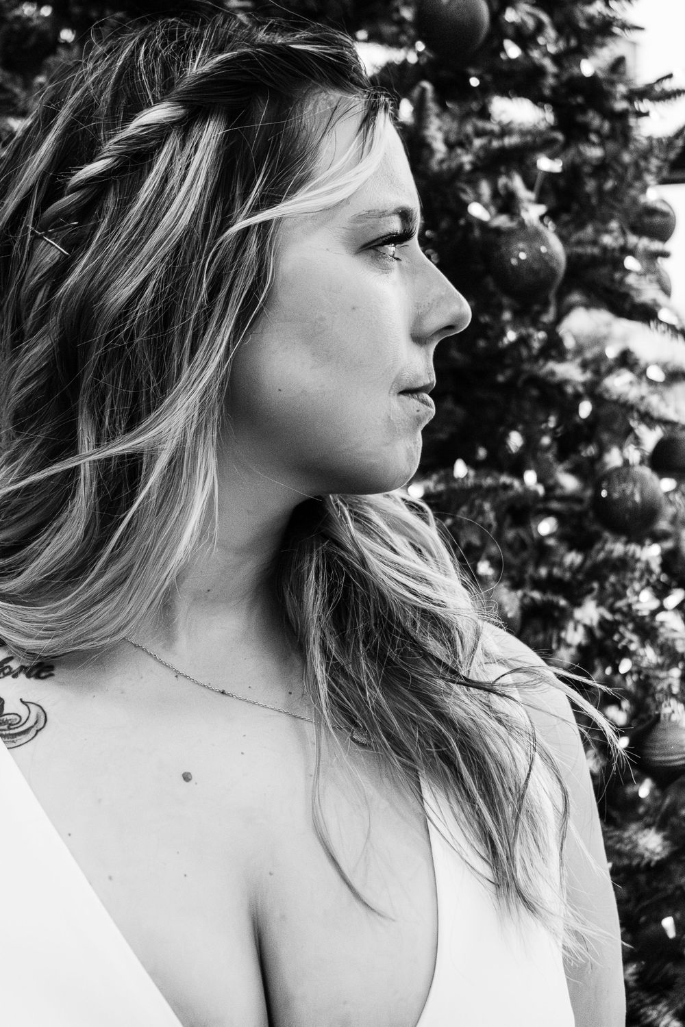A profile portrait in black and white with Christmas decorations in background.