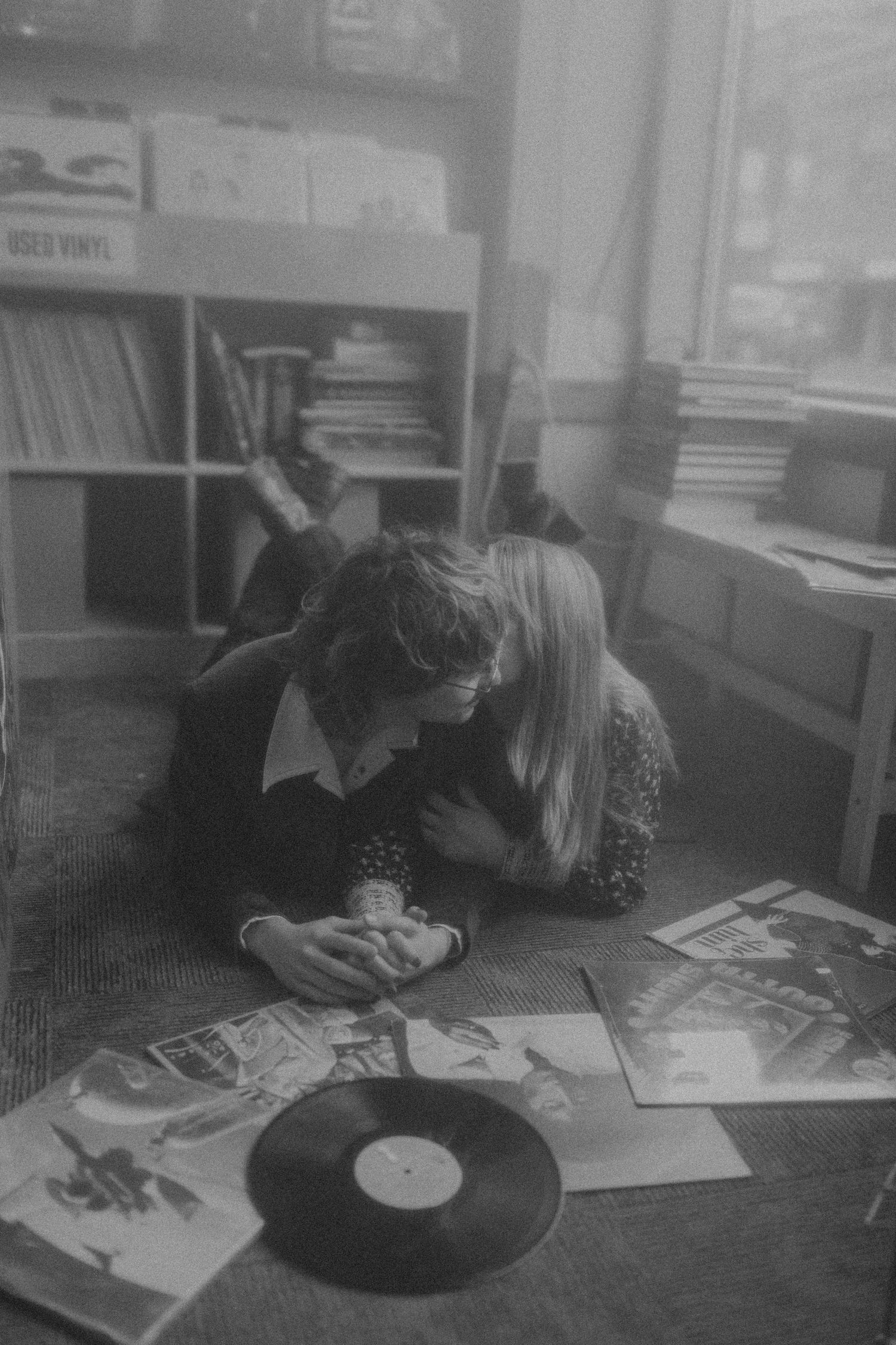 Person examining vinyl records and album covers on carpeted floor.