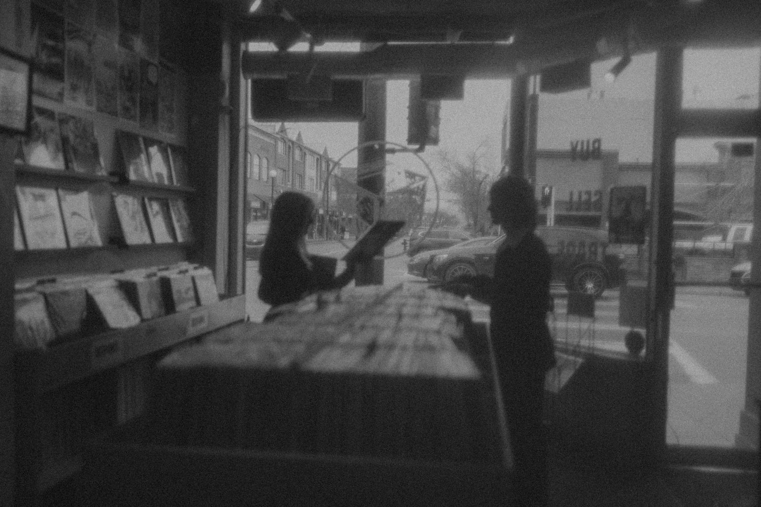 People browsing through vinyl records at a retro record store in a black and white photograph.