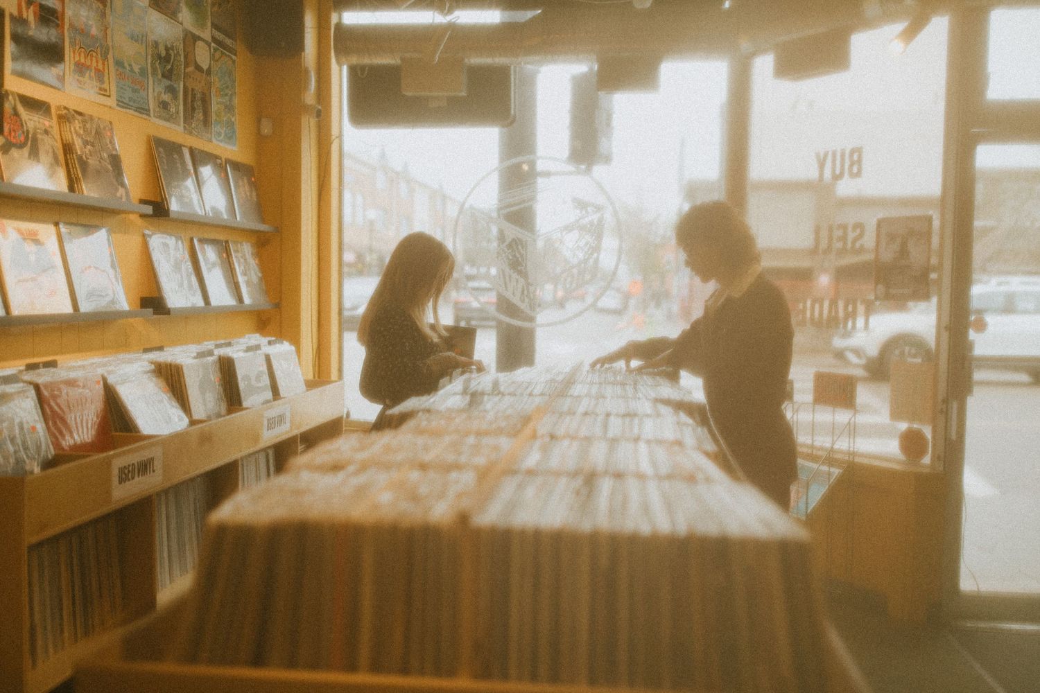 Silhouettes of customers browsing records in a vintage vinyl shop.