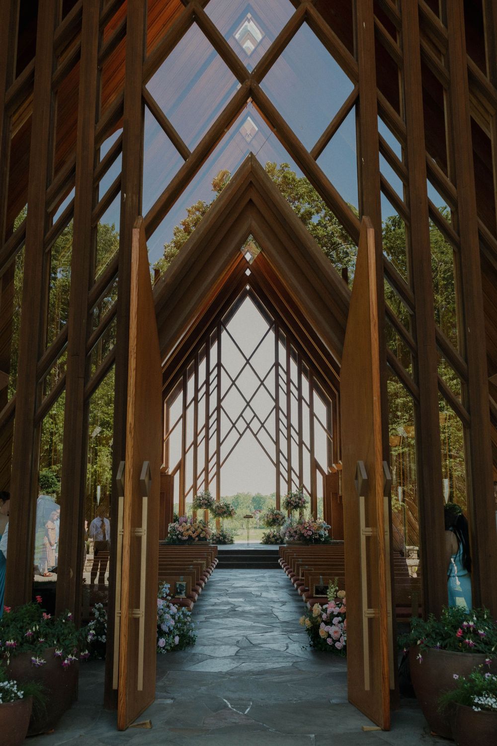 Interior view of a modern wooden chapel with dramatic angular beams and floral decorations.