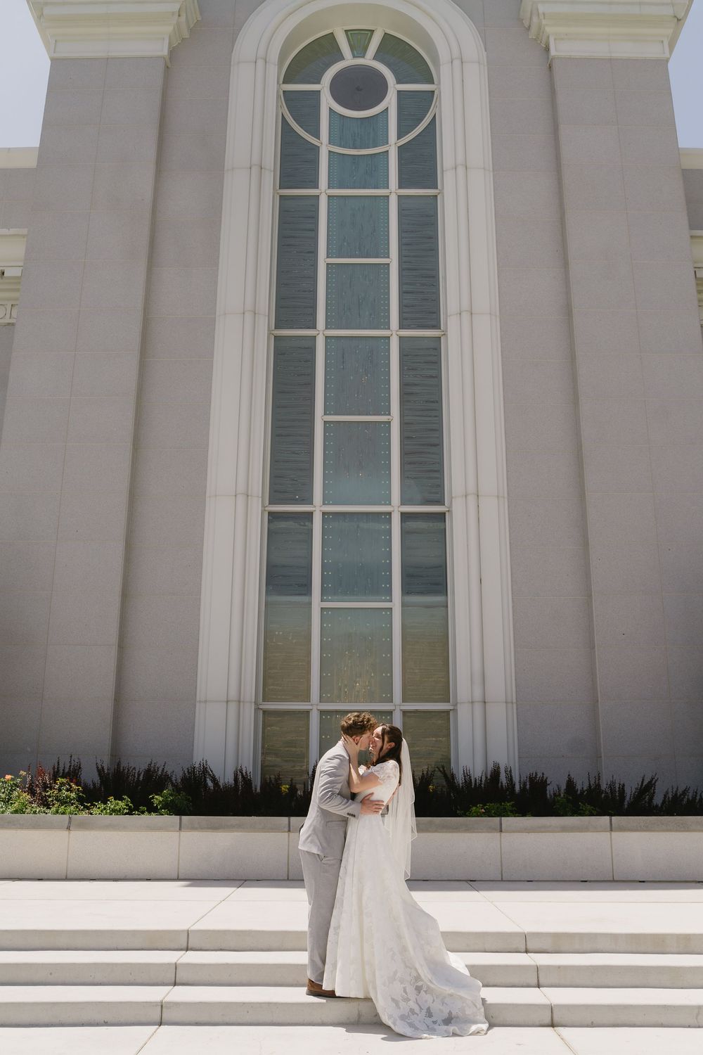 Wedding couple poses against white architectural columns of a grand building.