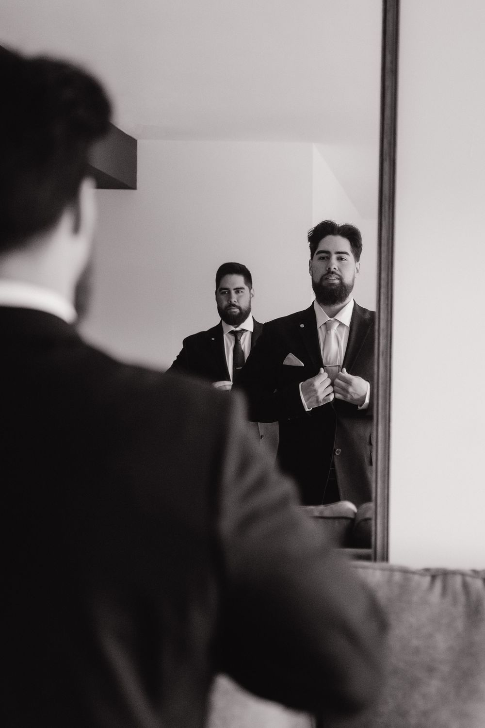 A sequence of black and white mirror reflections showing a man adjusting his tie while getting ready.