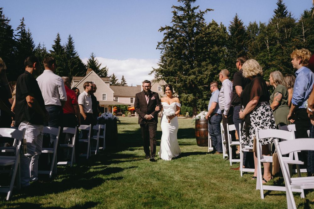 An outdoor wedding ceremony with white chairs lined up on grass under blue skies.