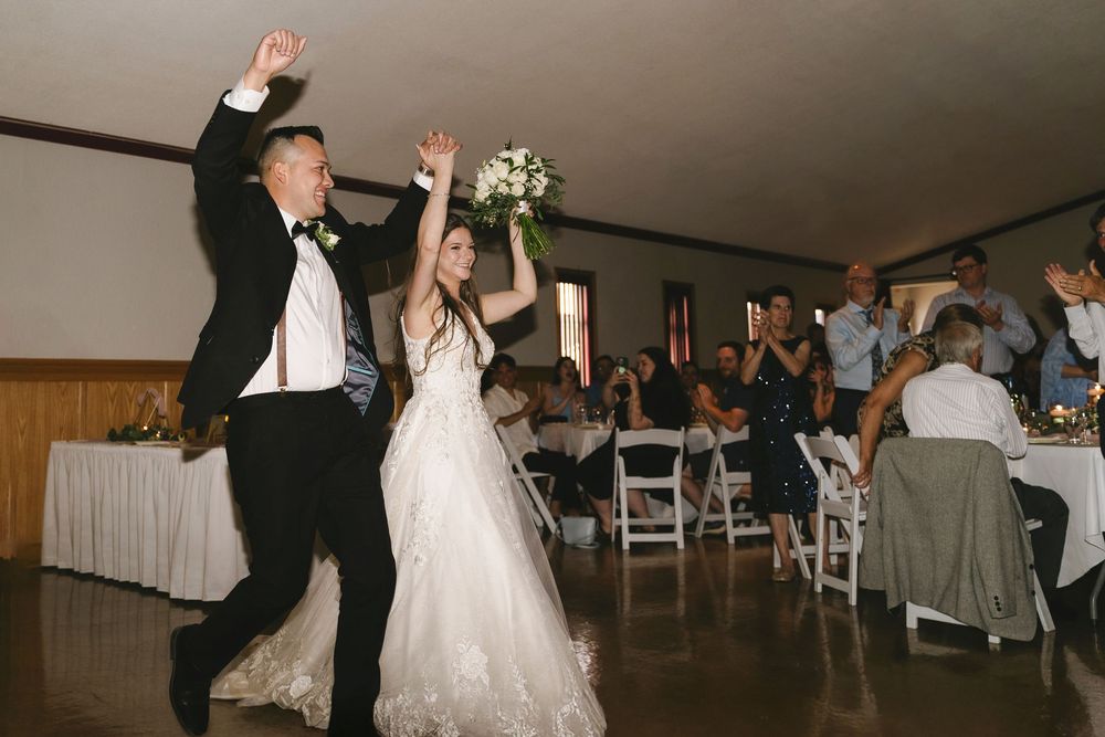 Wedding reception guests dance and celebrate on the dance floor during an indoor evening celebration.