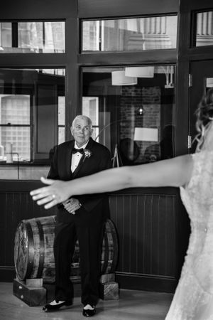 Emotional black and white photo showing an emotional first look moment of bride with grandfather in a tuxedo.