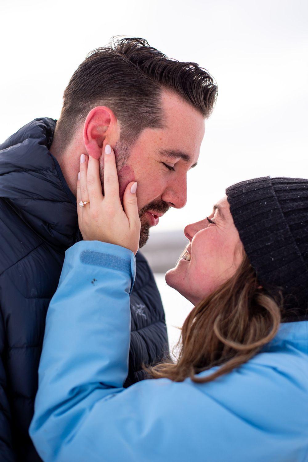 An intimate winter moment captured as a couple in warm coats shares a tender touch.