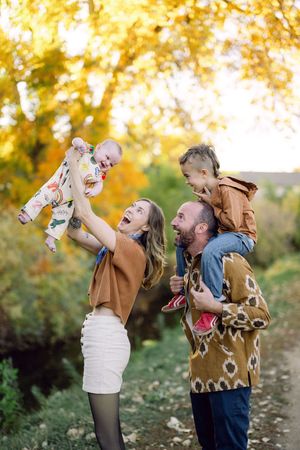 A joyful family moment captured in autumn with golden foliage in the background.