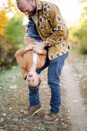 A heartwarming sequence of playful interaction between parent and child on an autumn path during golden hour.