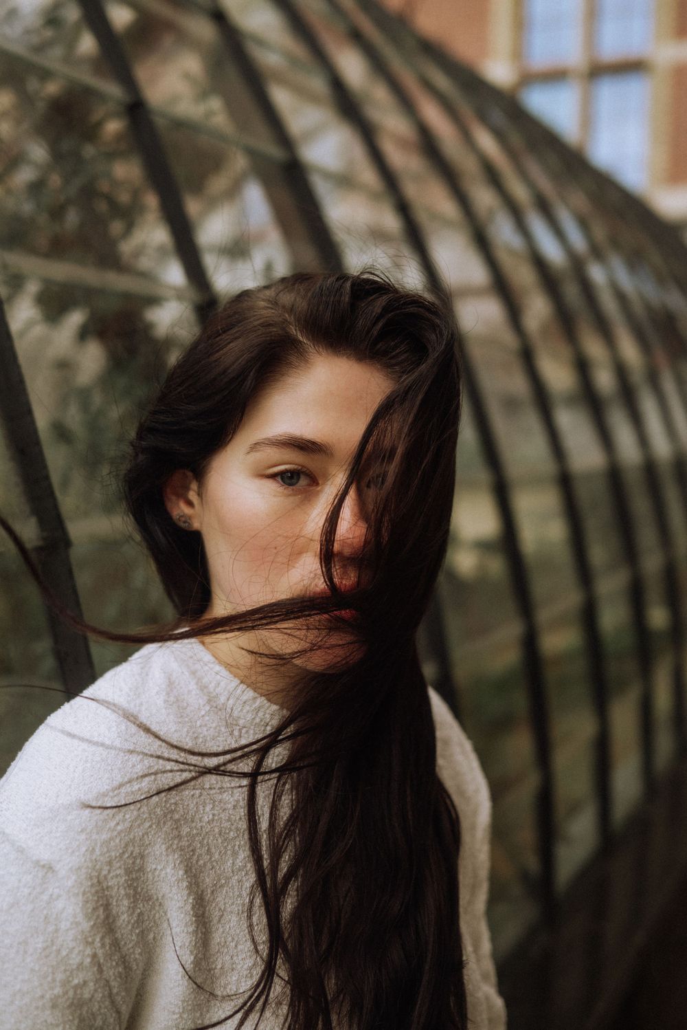 Artistic portrait series with natural light against a curved greenhouse structure.