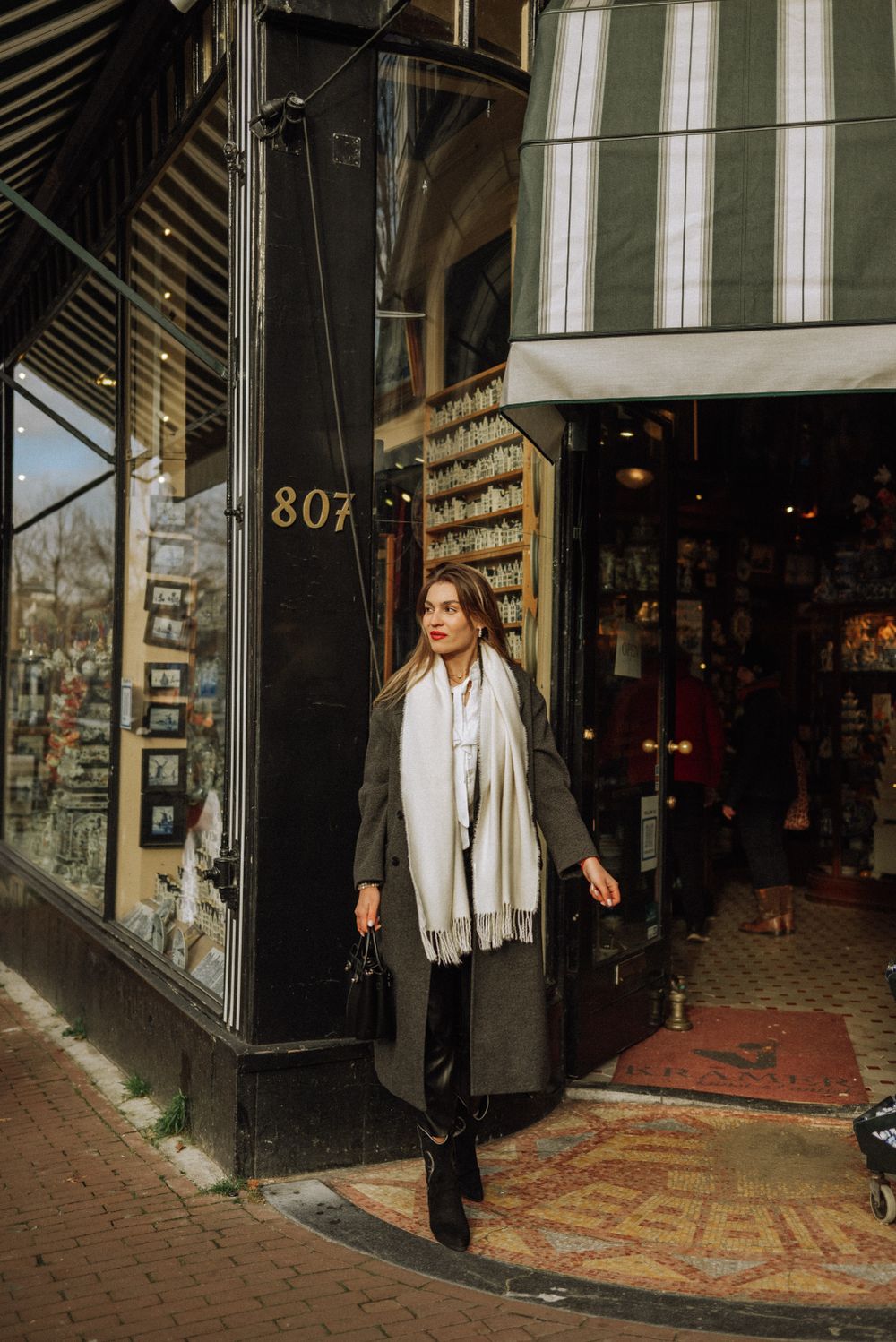 Stylish outfit captured outside vintage storefronts with oriental rugs displayed.