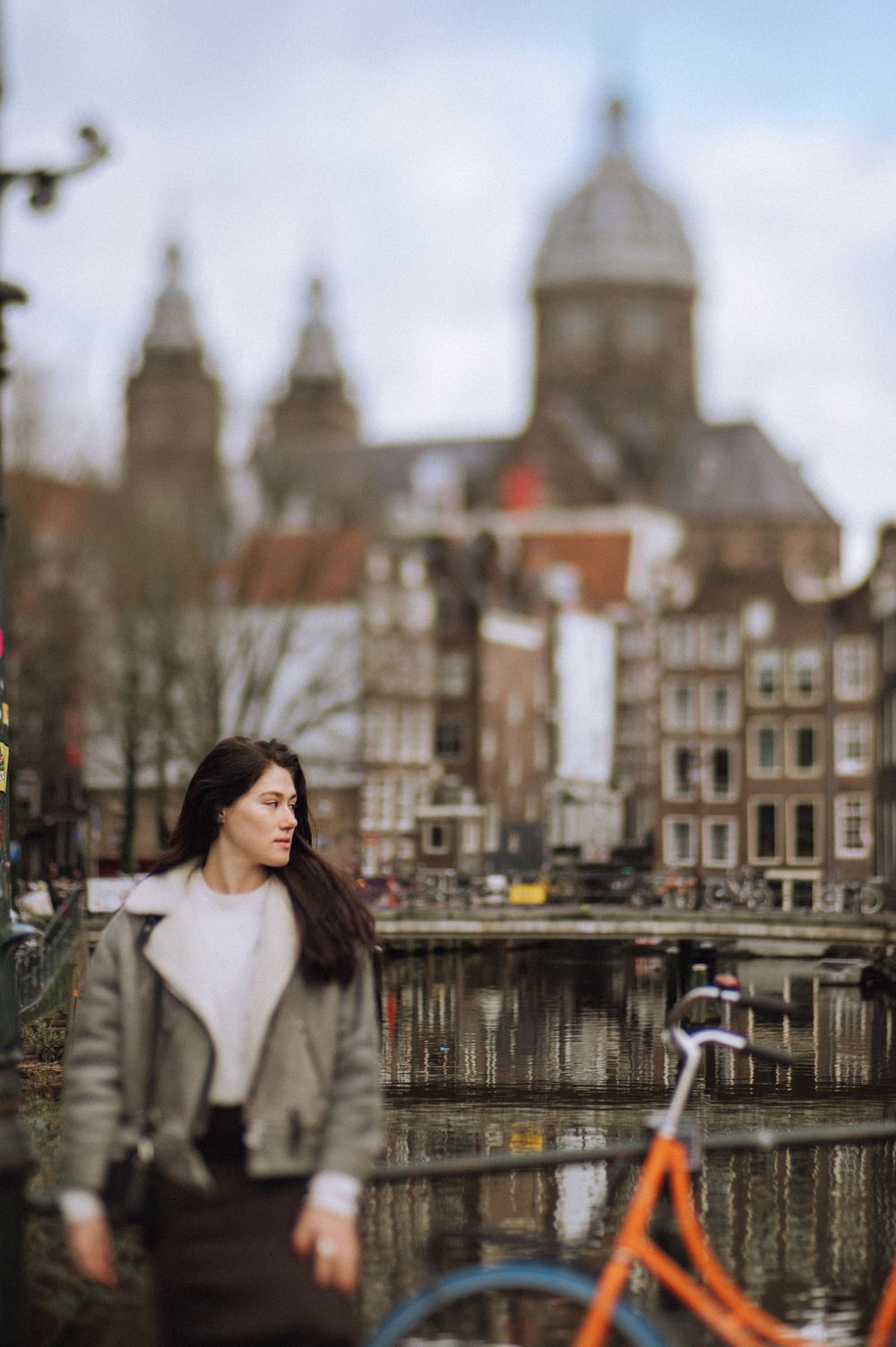 Moody urban photography with Amsterdam's historic canal houses and church spires in the background.