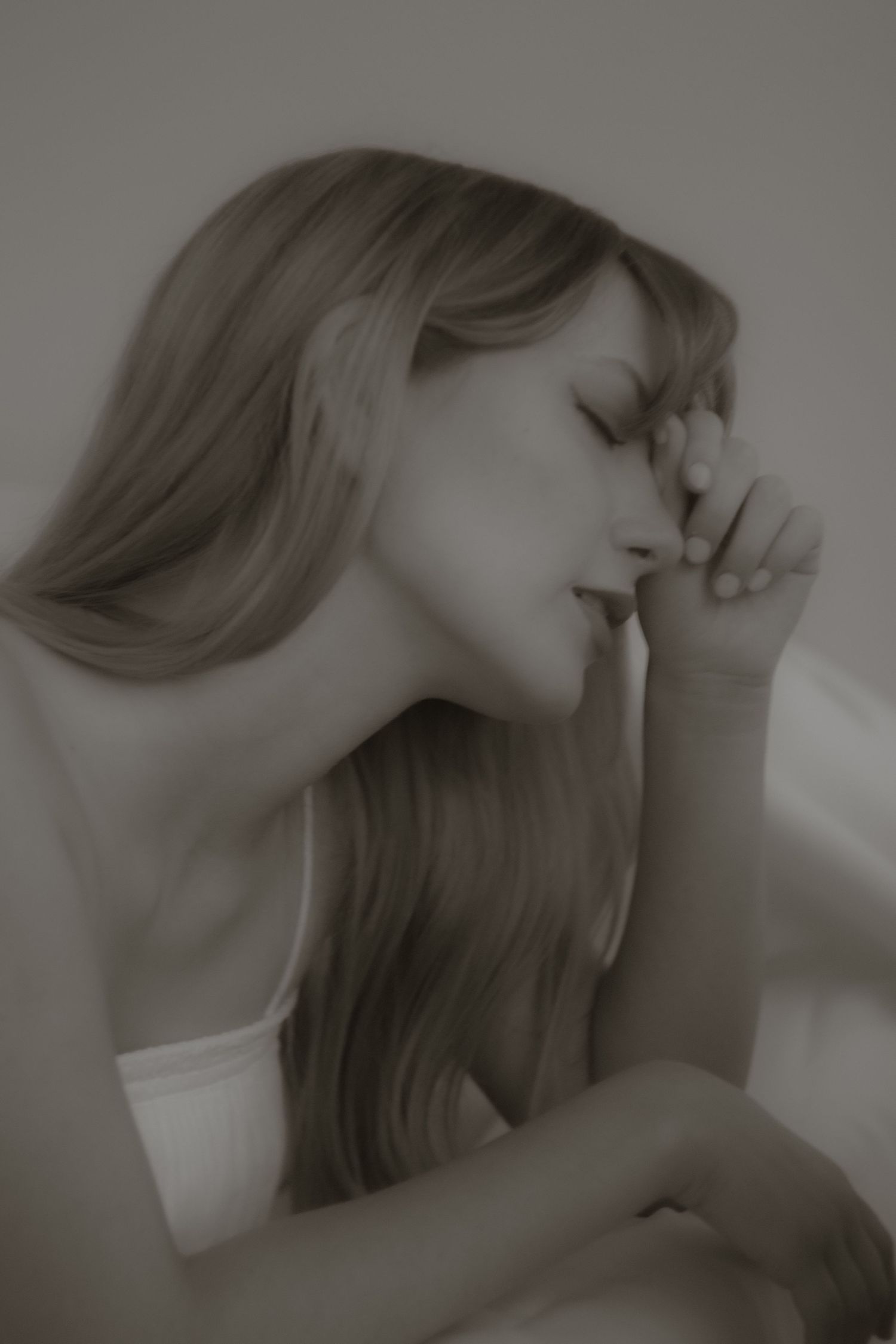Sepia-toned portrait of a pensive blonde woman resting her face on her hands.