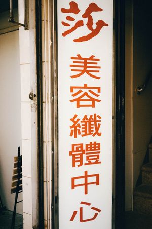 Red Chinese characters on a white vertical sign for a beauty and slimming center in Asia.