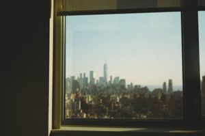 Stunning cityscape view of New York City skyline with One World Trade Center seen through a window.