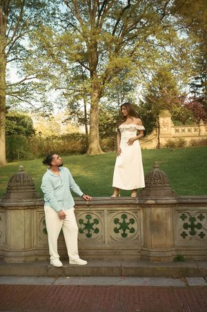 Couple posing at Bethesda Terrace in Central Park, man in mint suit looking up at woman in white off-shoulder dress.
