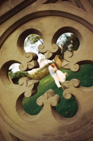 Stone decorative architectural detail with floral cutout pattern, couple visible through openings.