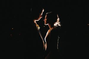 Dramatic lighting illuminates figures in a dark performance space.