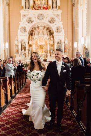 Wedding celebration inside an ornate church with elegant architecture and red carpeting.