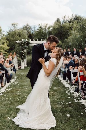 Dramatic wedding dip poses in a garden ceremony with flower petals scattered.