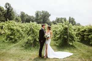 Wedding couple poses in a lush green garden setting with natural lighting.