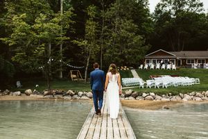 Wooden dock extends over a serene lake surrounded by lush green trees.