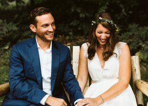 Couple shares intimate moments while seated outdoors in natural setting.
