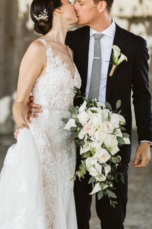 Romantic wedding portrait with elegant white bouquet and classic formal attire.