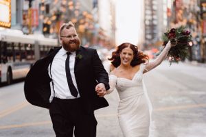 Newlyweds dancing and celebrating on an urban street at dusk.