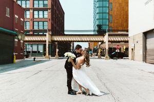 Urban wedding portrait with couple in dramatic pose between city buildings.