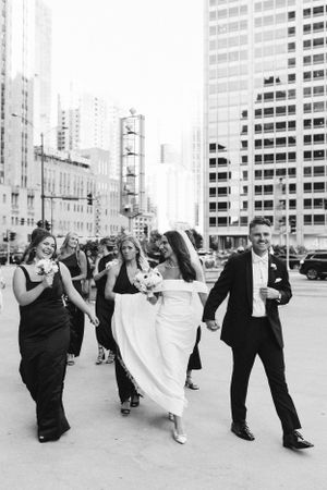Wedding party dancing and celebrating in front of urban buildings in black and white.