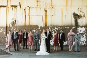 Wedding party poses against an industrial metal wall with rust patterns.