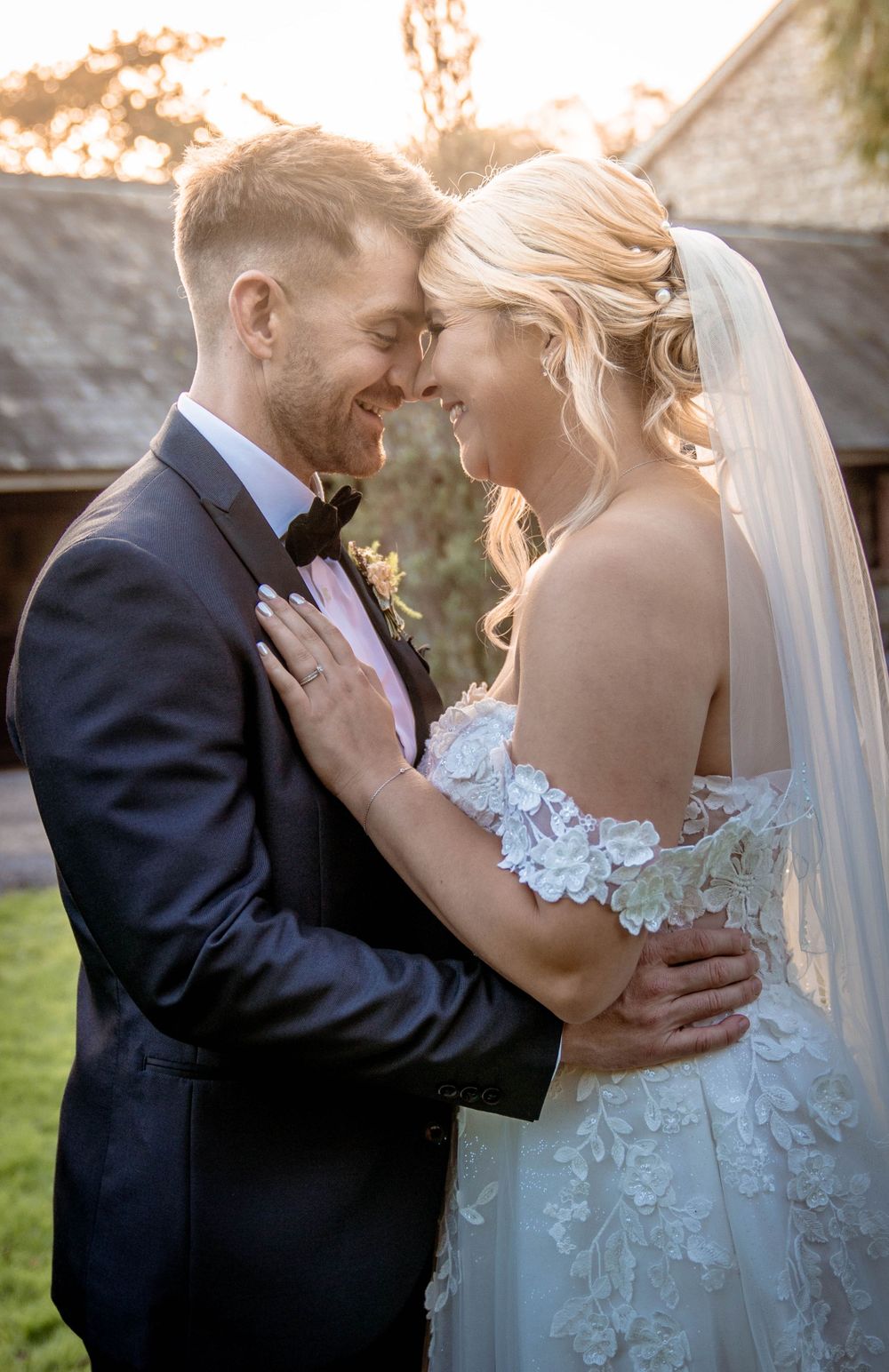 Intimate wedding photography with sunlight streaming through trees in a rustic outdoor setting.
