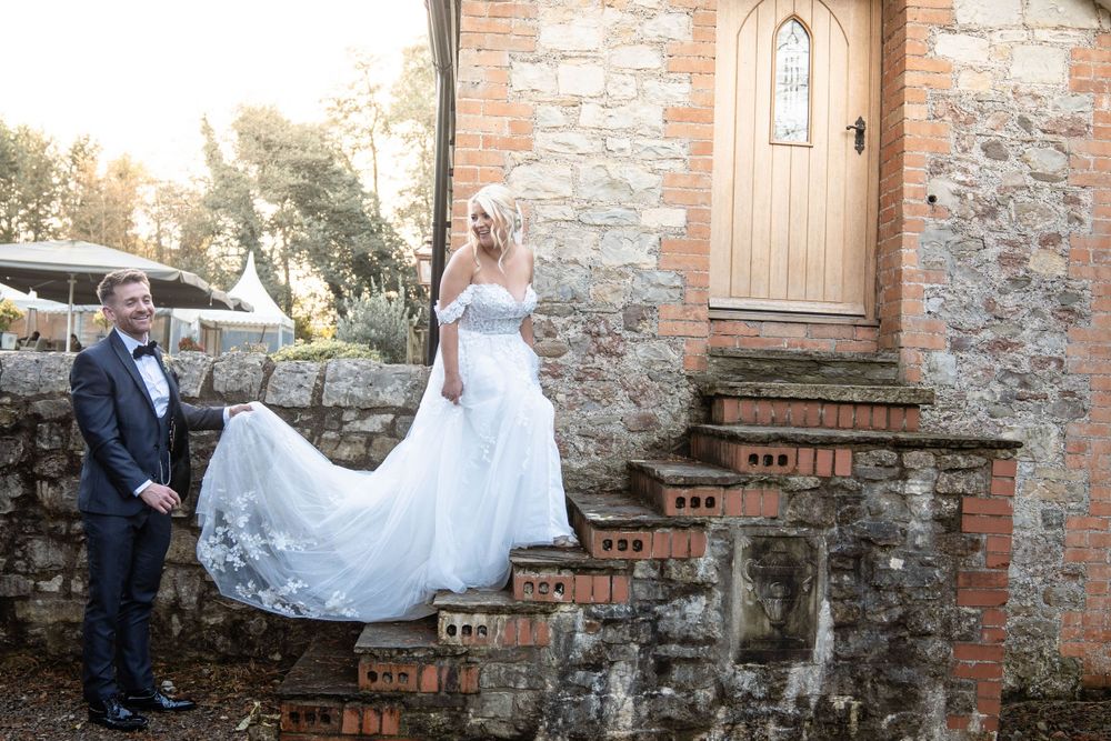 Wedding portraits against a historic stone wall with gothic architectural details.
