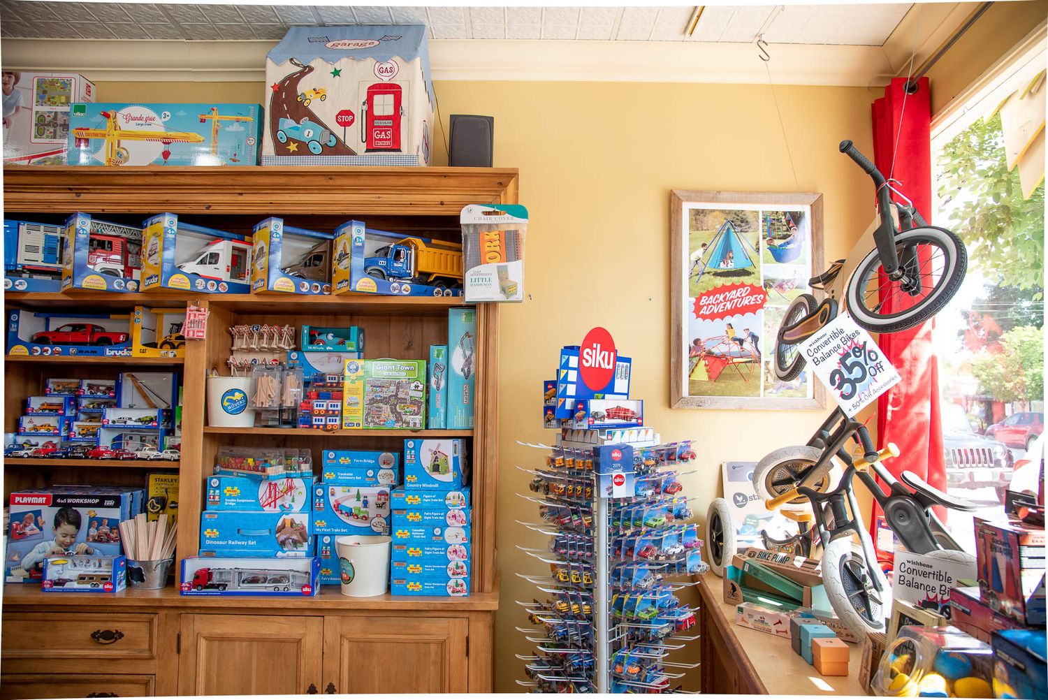 Retail store interior showing shelves stocked with merchandise and a red bicycle mounted on display near window.