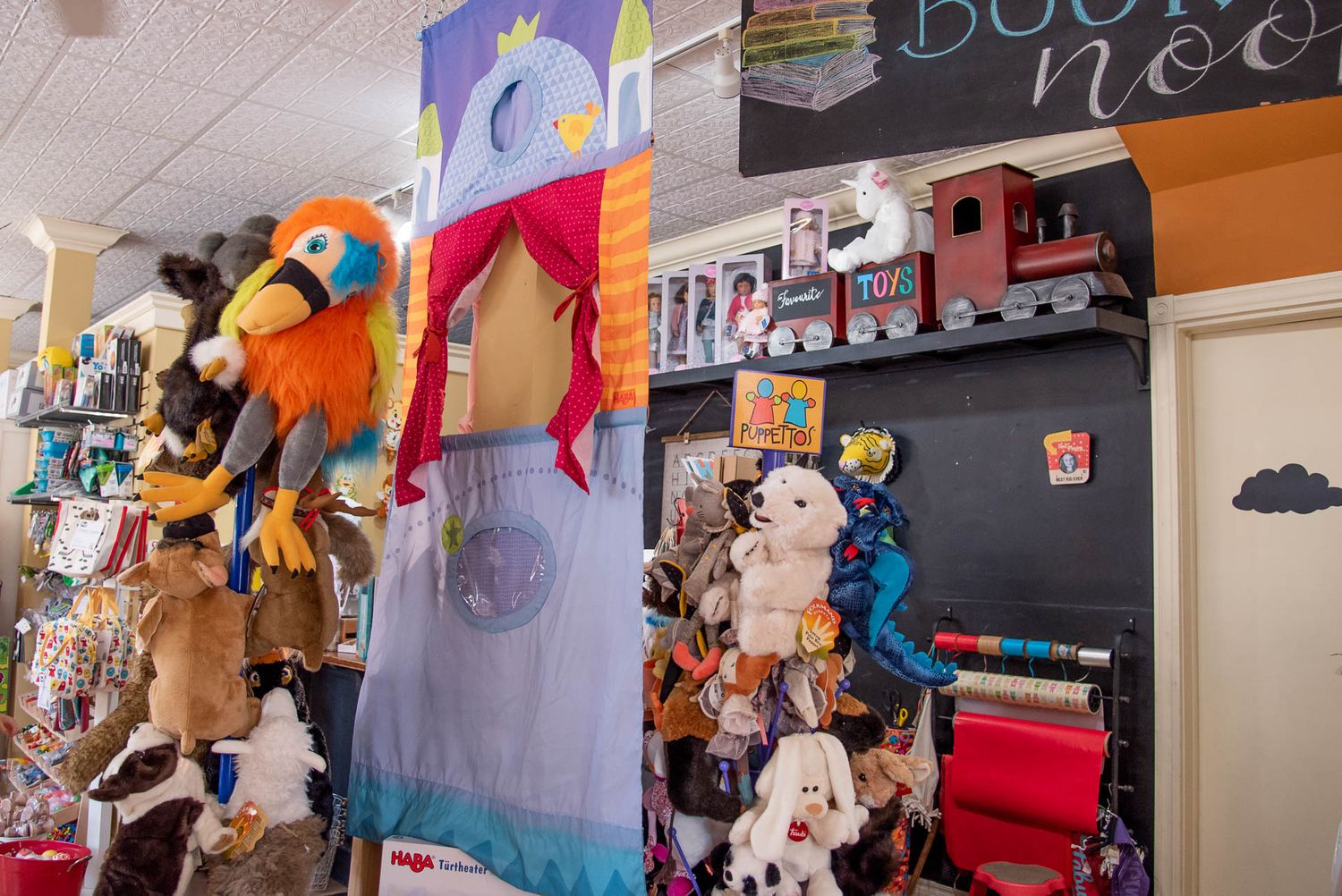 Plush toys and stuffed animals displayed on hanging racks in a whimsical toy store setting.