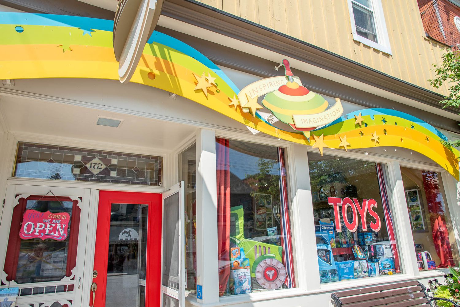 Colorful storefront of a toy shop with vibrant window displays and a painted mural above the entrance.