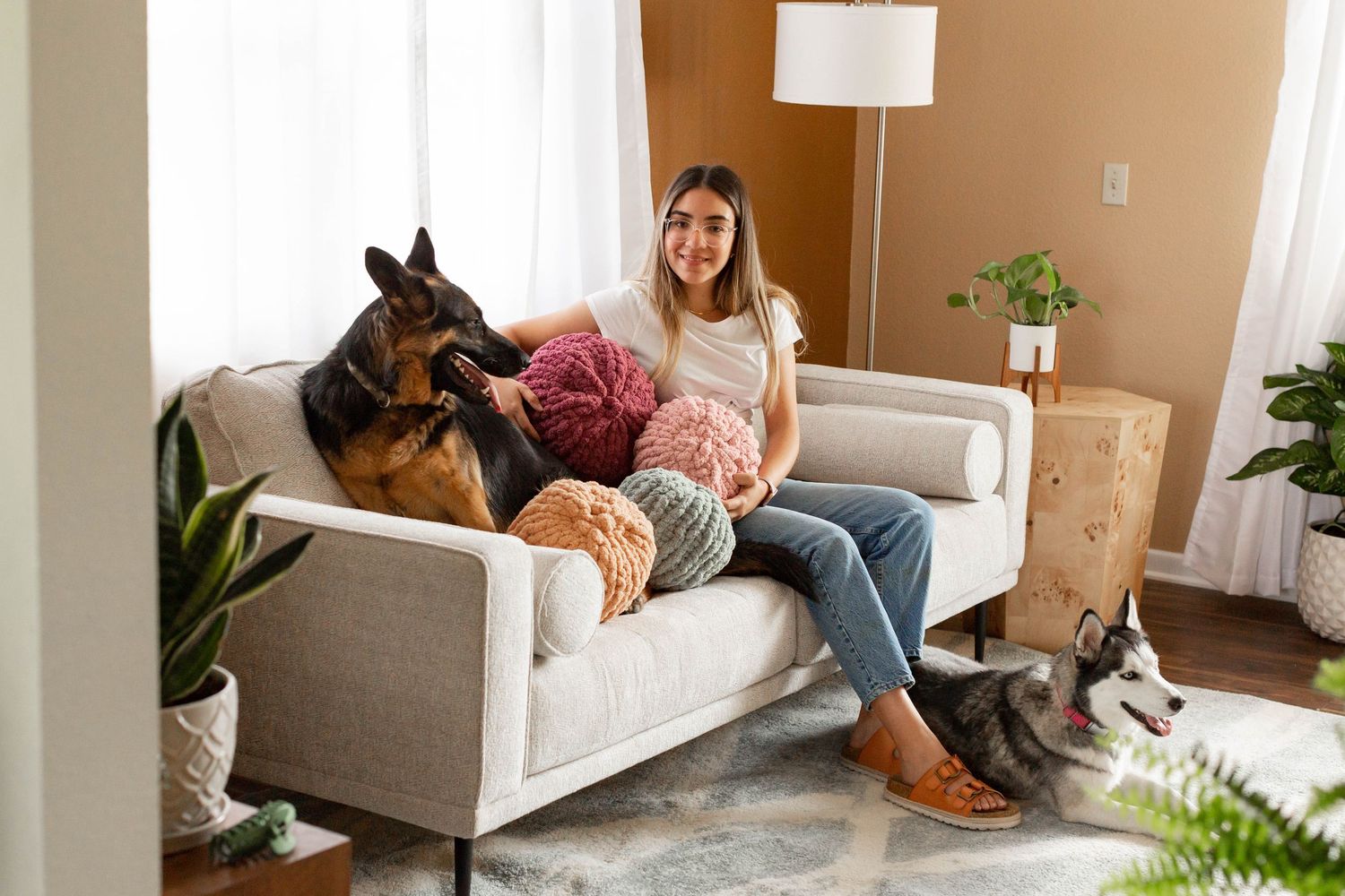 A relaxed scene on a gray couch with a German Shepherd, stuffed animals, and casual home decor in the background.