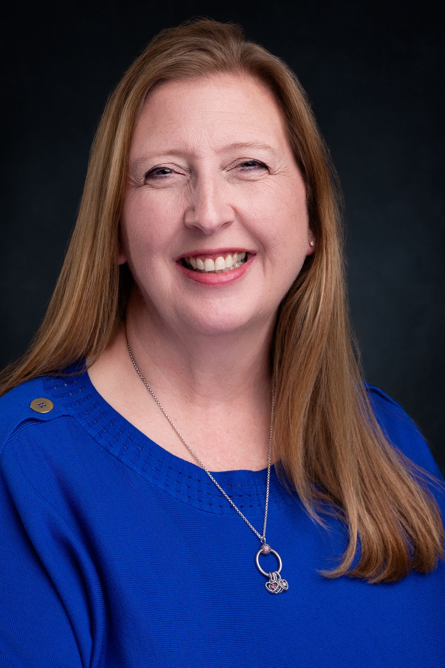 Studio headshot of a real estate agent from Dandridge in East Tennessee with a black background and royal blue sweater.