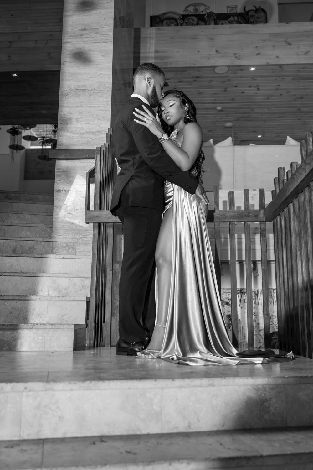 Romantic black and white portrait of couple embracing on wooden staircase.