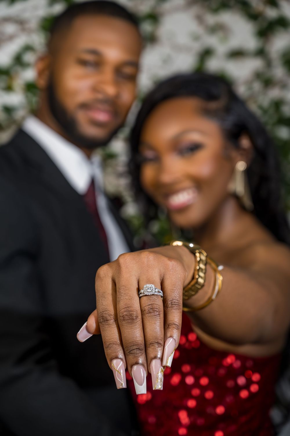 Close-up of elegant engagement ring with French manicure against formal attire.