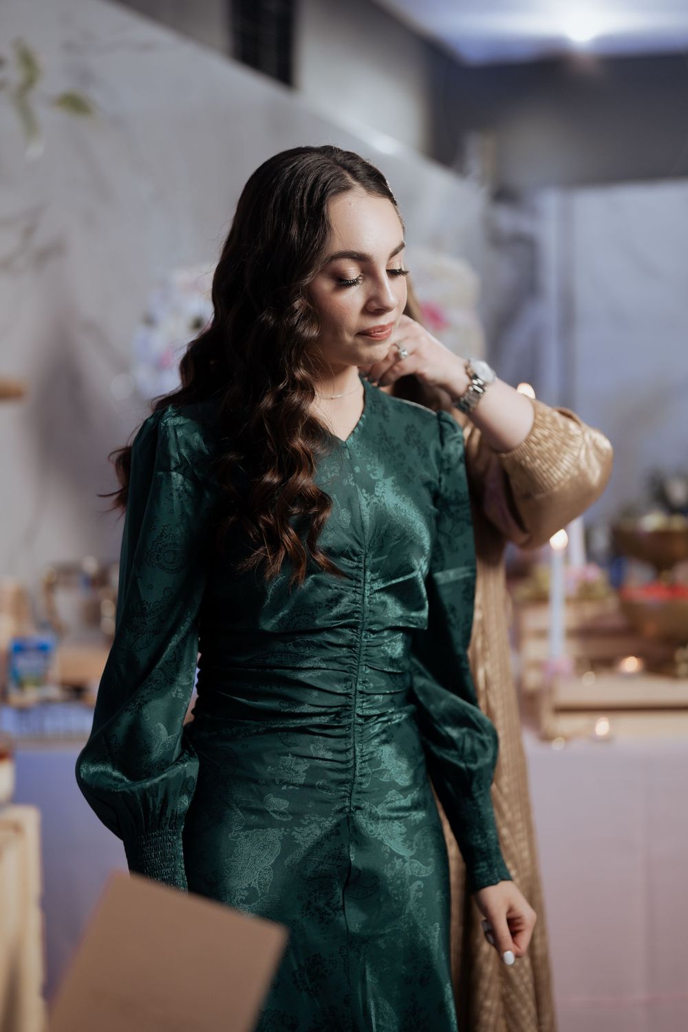 Woman in emerald green vintage-style dress poses elegantly indoors.
