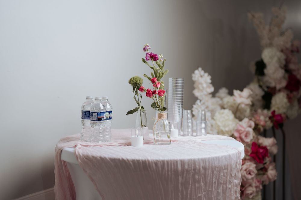 Minimalist wedding table setting with delicate pink florals in crystal vases.