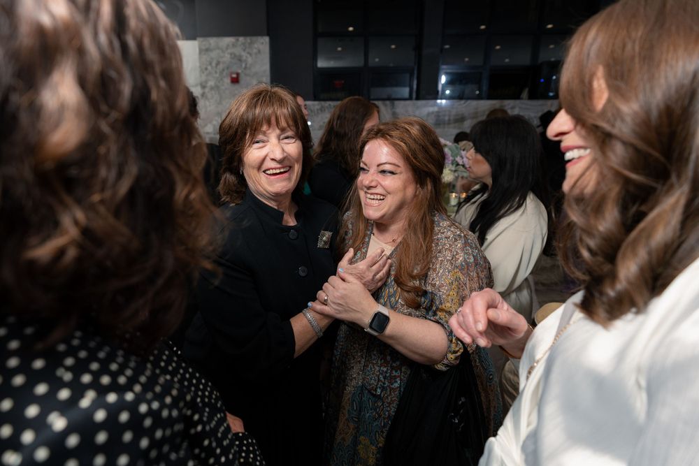 A group of people share joyful laughter at a celebration event.