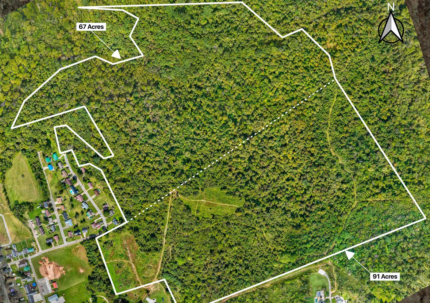 Aerial view of a forested property boundary marked with white lines showing parcel boundaries over green woodland.