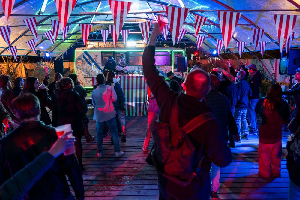 Crowd of people gathering at night under neon lights and geometric patterns at an entertainment venue.