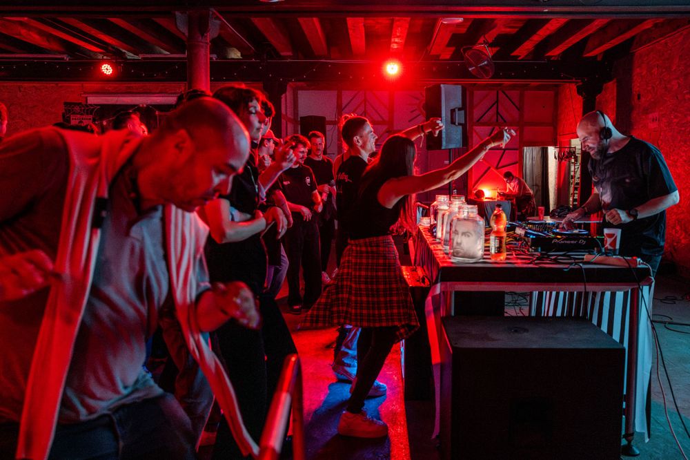 People enjoying a vibrant nightclub atmosphere with red lighting and DJ equipment.
