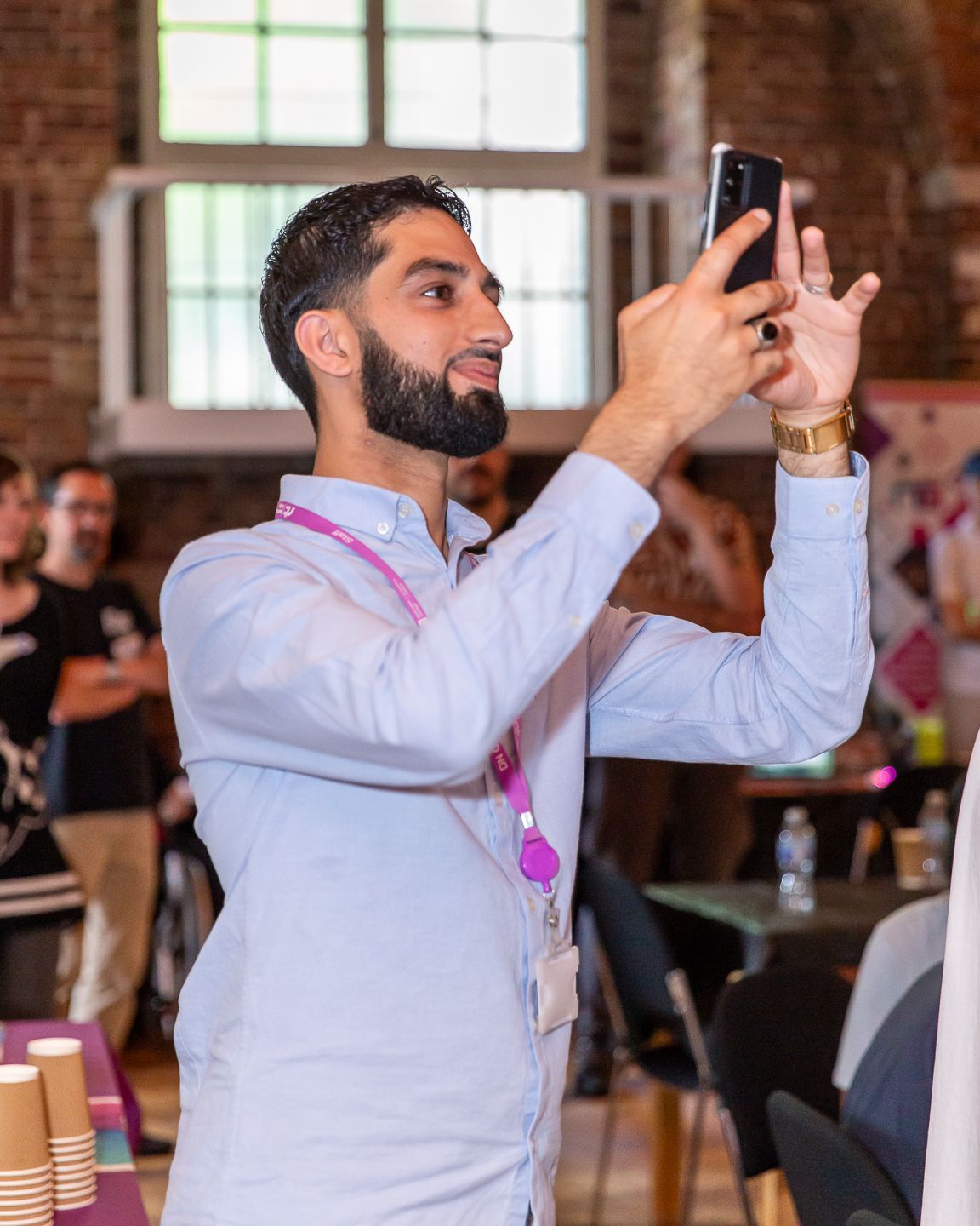Guest taking a photo on his mobile phone at the NextGen skills academy graduate showcase event held in London